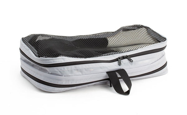 A filled and zipped closed Northwest Sky (light grey) Aether Small Laundry Aeronaut 45 Packing Cube mesh side up.